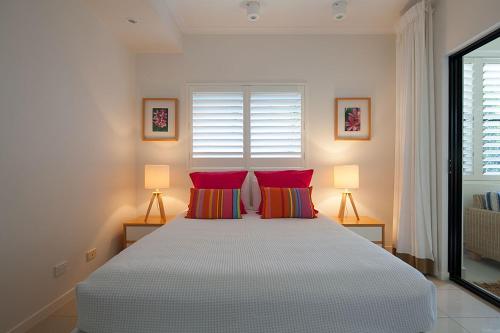 a bedroom with a large bed with red pillows at Papillon Coolum in Coolum Beach