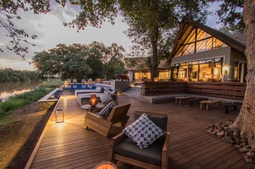 a deck with furniture and a building with a pool at Abelana River Lodge in Phalaborwa