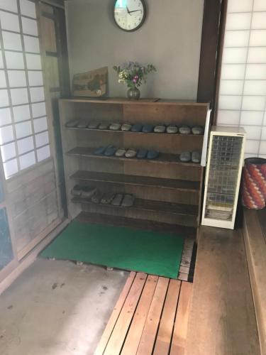 a room with a shelf with shoes and a clock at Taikoji Shukubo Hostel in Ise