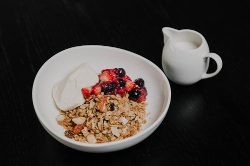 a bowl of granola with berries and a cup of milk at Hotel X Brisbane Fortitude Vly, Vignette Collection by IHG in Brisbane