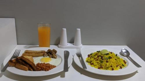a table with two plates of breakfast food and a glass of orange juice at Rockski Boutique Bed & Breakfast in Shillong