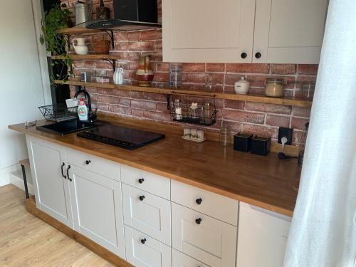 a kitchen counter with white cabinets and a brick wall at Dom z Sauną i Jacuzzi- na wyłączność lub pokoje in Serock