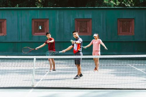 three men shaking hands on a tennis court at JW Marriott Phuket Resort and Spa in Mai Khao Beach