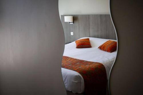a reflection of a bedroom with a bed in a mirror at Hôtel Le Nautic in Arcachon