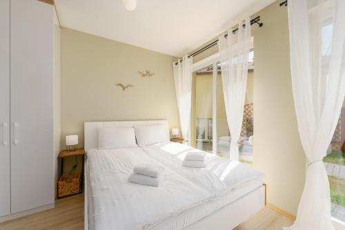 een witte slaapkamer met een wit bed en een raam bij Zdrojowa 5A by Renters in Międzyzdroje