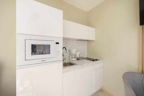 a white kitchen with a sink and a microwave at Zdrojowa 5A by Renters in Międzyzdroje