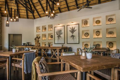 a restaurant with wooden tables and chairs and pictures on the wall at Abelana River Lodge in Phalaborwa