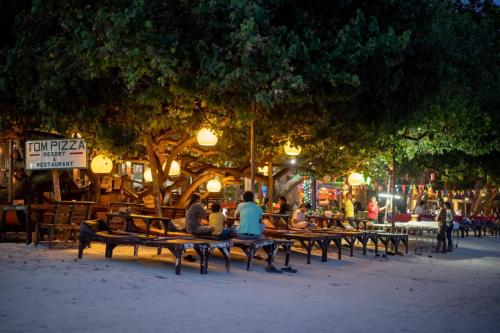 a group of people sitting on park benches at night at Tom Pizza Resort in Ko Samed