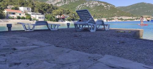 two chairs sitting on a beach next to the water at Apartman Bebic in Klek