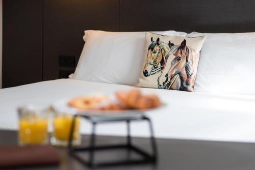 a tray of donuts on a bed with two horses pillows at Hotel Osteria della Pista dal 1875 in Casorate Sempione