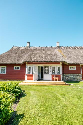 a red and white house with a grass yard at Käbruotsa farmhouse in Ruhve