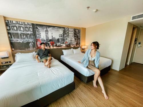 una mujer y un niño sentados en las camas en una habitación de hotel en GLOW Pattaya, en Pattaya South