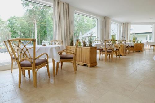 a dining room with tables and chairs and large windows at Hotel Residenz WALDOASE in Ahlbeck