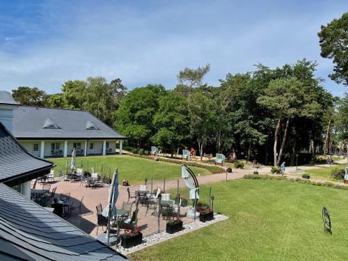 a patio with chairs and umbrellas in a yard at Hotel Residenz WALDOASE in Ahlbeck