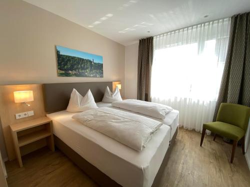 a bedroom with a white bed and a green chair at Hotel-Restaurant und Gästehaus Löwen in Süßen