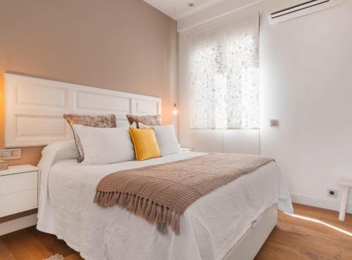 1 dormitorio con 1 cama blanca grande con almohadas amarillas en ALCALA III, en Madrid