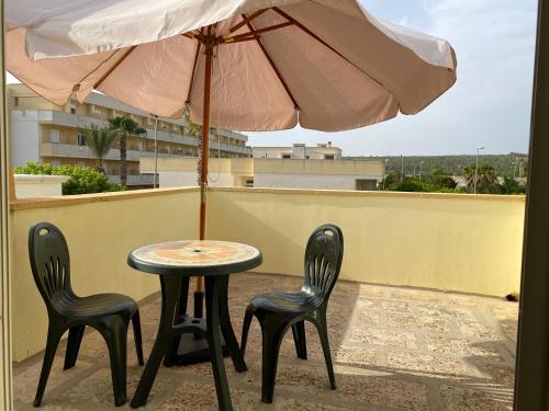 a table and two chairs and an umbrella on a balcony at Villetta Sabbia d'Oro in Torre Mozza
