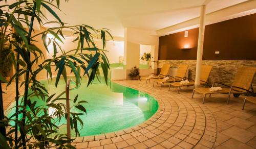 a pool in a hotel lobby with chairs and a plant at Christophs Hotel in Schenna