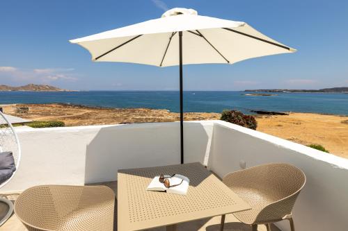 a table and chairs with an umbrella on a balcony at Sea & Sun Paros in Naousa