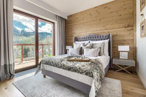 a bedroom with a bed and a large window at Tatra Resort & SPA in Kościelisko