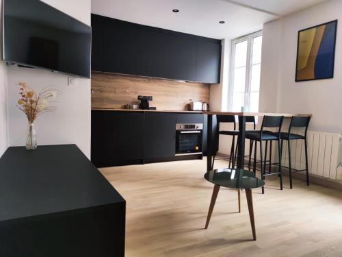 a kitchen with black cabinets and a bar with stools at My Duplex House Trouville in Trouville-sur-Mer