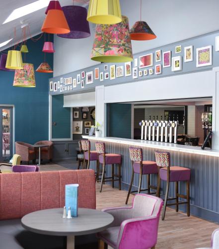 a restaurant with chairs and a bar with colorful lights at The Lodge Hotel in Coleraine