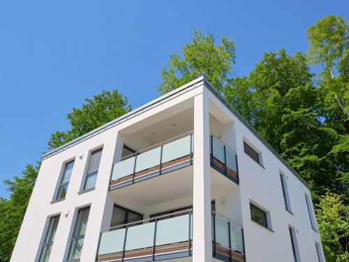 a white building with trees in the background at Haus Arkona Penthouse - Strandräuber in Ostseebad Sellin