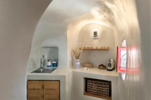 cocina con fregadero y chimenea en una habitación en White Cave by Caldera Houses, en Oia