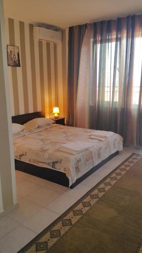 a bedroom with a bed and a window with curtains at На гости при Силвия in Obzor