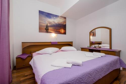 a bedroom with a large bed with purple sheets and a mirror at Apartment in Mundanije with Seaview, Terrace, Air condition, WIFI (3748-2) in Mundanije