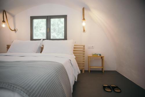 a bedroom with a bed and a pair of shoes at Exi Sea Side Suites in Perissa
