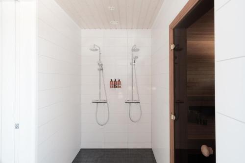 a bathroom with a shower with white tiles at Seija's Modern Secluded Villa with Jacuzzi & Sauna in Töfsala