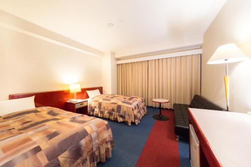 um quarto de hotel com duas camas e um sofá em Hotel Sunrise Inn em Kaizuka