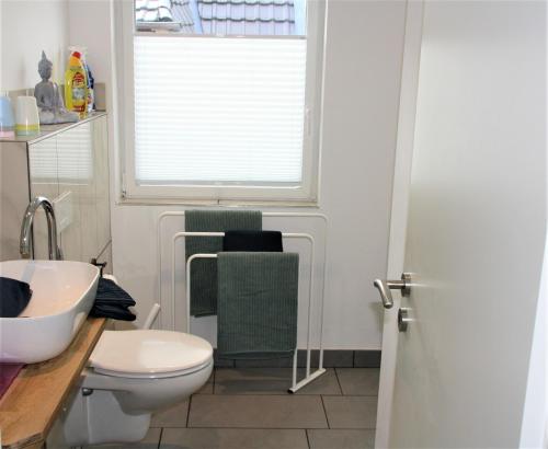 La salle de bains est pourvue de toilettes, d'un lavabo et d'une fenêtre. dans l'établissement Ferienwohnung Heimelich, à Rastede