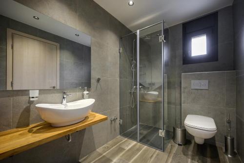 a bathroom with a sink and a shower and a toilet at Serenity Villas in Develíkia