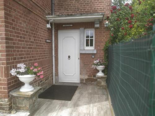 a white door in a brick building with two vases at Julienne5 in Blégny