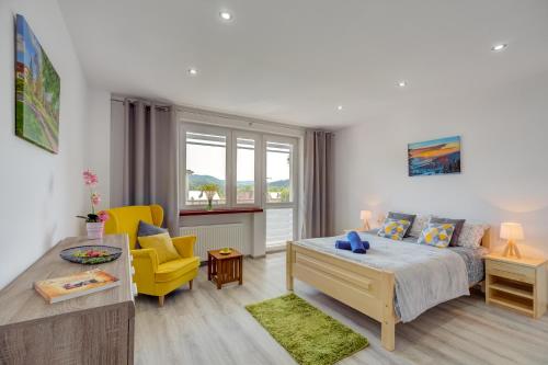 a living room with a bed and a yellow chair at Tylicki Zakątek in Tylicz