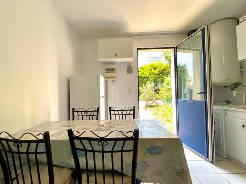 une cuisine avec une table, des chaises et un réfrigérateur dans l'établissement REF 008 Maison T2 à Tumiac entre Océan et Golfe du Morbihan, à Arzon