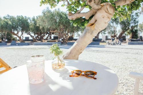 a table with glasses on it next to a tree at Exi Sea Side Suites in Perissa