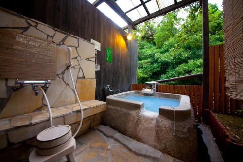 a bathroom with a tub with a toilet and a sink at Yufuin Yasuha in Yufuin