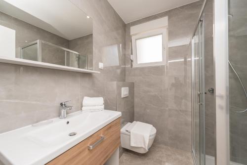 La salle de bains est pourvue de toilettes, d'un lavabo et d'une douche. dans l'établissement Sara luxury apartment with a pool, à Novalja
