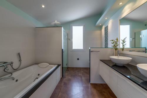 ein Badezimmer mit zwei Waschbecken, einer Badewanne und einem Tubermott in der Unterkunft Villa Santandria Grupo Seranova Luxury Hotel in Ciutadella