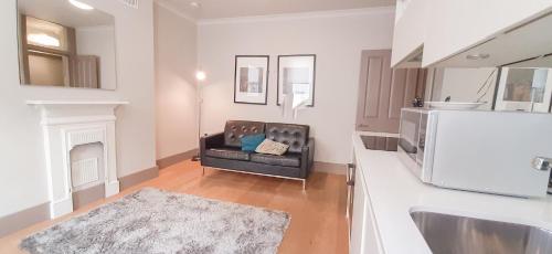 a living room with a black couch in a kitchen at One Bed Serviced Apts near Oxford Street upper ground in London