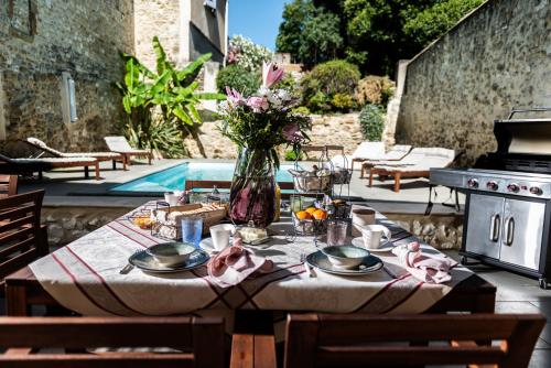 una mesa con platos de comida y un jarrón de flores en LA MAISON DE LIVIA, chambres et table d'hôtes, en Sauzet