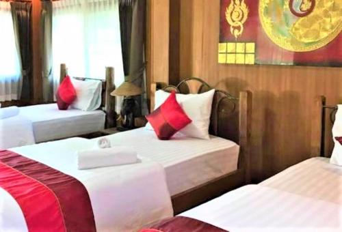 a hotel room with two beds with red pillows at Papai Country Lodge SHA in Ban Mae Pong