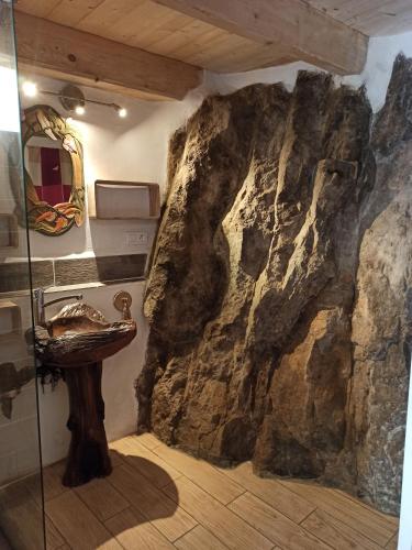 - une salle de bains avec un mur en pierre à côté d'un lavabo dans l'établissement Gîte les coquelicots de Retourtour, à Lamastre