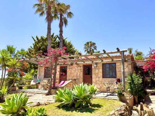 a house with palm trees and pink flowers in front of it at Quinta do Mar - Country & Sea Village in Luz