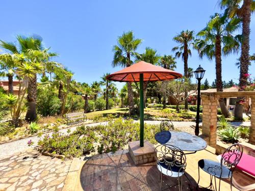 a patio with a table and chairs and an umbrella at Quinta do Mar - Country & Sea Village in Luz