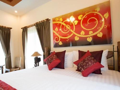 a bedroom with a white bed with red pillows at Papai Country Lodge SHA in Ban Mae Pong