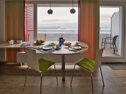 einen Tisch und Stühle in einem Zimmer mit Fenster in der Unterkunft Apartmenthaus Hohenfels in Helgoland